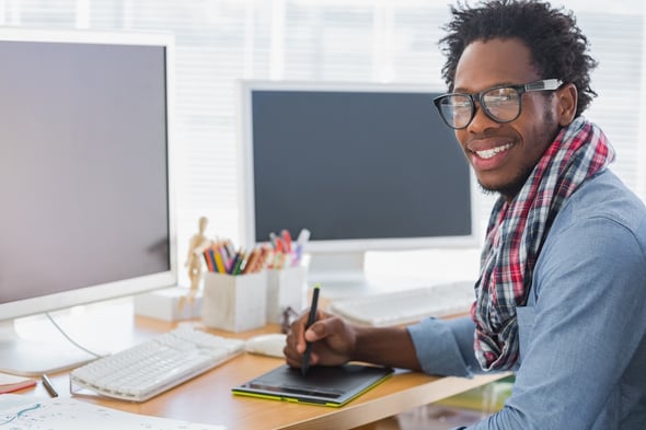 Smiling graphic designer using a graphics tablet in a modern office